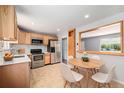 Modern kitchen featuring stainless appliances, wood cabinets, tile backsplash and a dining table at 16720 E Layton Ave, Aurora, CO 80015