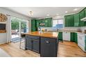 Bright kitchen features green cabinets, butcher block island, and sliding doors to the outdoor deck at 6808 Silverleaf Ave, Firestone, CO 80504