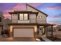 Charming two-story home at twilight featuring a front-facing garage, a welcoming porch, and modern architectural details at 10052 Zeno St, Commerce City, CO 80022