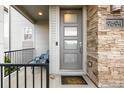 Inviting front porch with a modern door and stacked stone accents at 9694 Dunning Cir, Highlands Ranch, CO 80126