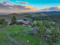 Scenic aerial view of a log home surrounded by lush greenery, hills, and a distant mountain range at 51 West Ranch Trl, Morrison, CO 80465