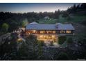Beautiful log home featuring a stone foundation, metal roof, and picturesque hillside setting at dusk at 51 West Ranch Trl, Morrison, CO 80465