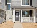 Close-up of a charming townhome showcasing a stone facade, gray wood siding, and a welcoming front porch at 6581 N Malaya St, Aurora, CO 80019