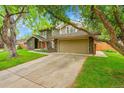 Charming exterior view of the home, featuring an attached two car garage and mature trees at 4012 S Newport Way, Denver, CO 80237