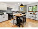 Charming kitchen featuring light hardwood floors, a wood island, white cabinets, and modern lighting at 9400 E Iliff Ave # 292, Denver, CO 80231