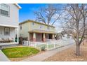 This two-story home features a brick foundation, complemented by a manicured lawn and a classic white picket fence at 109 Cantril St, Castle Rock, CO 80104