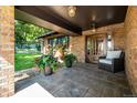 Inviting covered front porch with stone flooring, brick columns, potted plants, and a cozy armchair at 6740 S Windermere St, Littleton, CO 80120