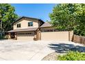 Spacious three-car garage with brick accents and a wide concrete driveway, surrounded by lush greenery at 6740 S Windermere St, Littleton, CO 80120