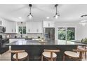 Modern kitchen with white cabinets, stainless steel appliances, a black island and stylish pendant lighting at 11877 Keough Dr, Northglenn, CO 80233