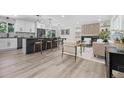 Open-concept layout seamlessly connecting the kitchen to the living room with wood floors and bright lighting at 11877 Keough Dr, Northglenn, CO 80233