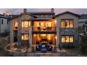 Stunning two-story home with stone accents, balconies, and outdoor seating areas at dusk at 8310 Raphael Ln, Littleton, CO 80125