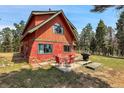 Backyard patio with outdoor seating and a grill, perfect for entertaining in a serene, wooded setting at 26526 Gray Buck Trl, Conifer, CO 80433