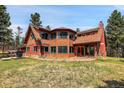The exterior view showcases a unique home design, set amidst a lush, wooded landscape at 26526 Gray Buck Trl, Conifer, CO 80433