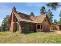 Rustic exterior showcases unique architecture with stone accents and a well-maintained lawn at 26526 Gray Buck Trl, Conifer, CO 80433