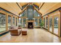 Bright living room featuring vaulted ceilings, wood floors, a stone fireplace, and picturesque forest views at 26526 Gray Buck Trl, Conifer, CO 80433