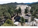 Aerial view of a beautiful home, an outdoor stone patio, and lush greenery with a mountain backdrop at 24949 N Mountain Park Dr, Evergreen, CO 80439