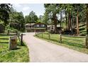 A green two-story house set among tall trees, features a long driveway and rustic wooden fence at 24949 N Mountain Park Dr, Evergreen, CO 80439