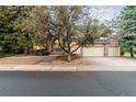 Beautiful home featuring a brick exterior, mature trees, and a two-car garage with brick paver driveway at 16416 E Powers Pl, Centennial, CO 80015