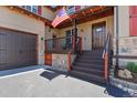Close-up of home's entrance, featuring a covered porch, wood door, and stone detailing near garage at 7947 Monarch Rd, Larkspur, CO 80118