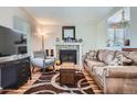 Spacious living room featuring a stone fireplace, hardwood floors, and comfortable seating for relaxation and entertaining at 8438 Prairie Clover Way, Parker, CO 80134