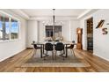 Bright dining room with wood floors, modern chandelier, and large window showcasing natural light at 10968 Lewiston St, Commerce City, CO 80022