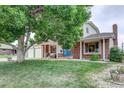 Beautiful home with a large tree in the front yard, a well-maintained lawn, and a cozy front porch at 10137 W Berry Dr, Littleton, CO 80127