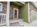 Inviting front entrance with stone accents, a covered porch, and a wood-framed front door at 676 Hearthstone Ave, Brighton, CO 80601