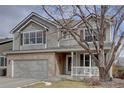 Inviting two-story home with a two-car garage, brick accents, and charming covered porch at 14656 W Vassar Dr, Lakewood, CO 80228