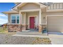 Charming front entrance showcasing a red door, stone accents, and covered porch at 497 Valley Way, Bennett, CO 80102