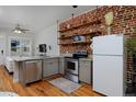 Stylish kitchen featuring stainless steel appliances, exposed brick wall, and open shelving at 2424 N Clay St, Denver, CO 80211