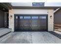 Attached two-car garage with dark wood door that complements the light stone exterior and dark trim at 23652 E 40Th Ave, Aurora, CO 80019