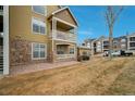 Condominium featuring dual balconies with a stone facade and tan siding at 6021 W Castlegate Dr # E18, Castle Rock, CO 80108