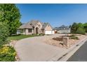 Beautiful tan brick home with a three car garage, circular driveway, and a xeriscaped front yard at 4245 S Dawson St, Aurora, CO 80014