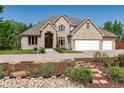 Beautiful tan brick home with a three car garage and a well manicured front yard and flower beds at 4245 S Dawson St, Aurora, CO 80014