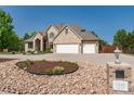Beautiful tan brick home with a three car garage, concrete driveway, and a xeriscaped front yard at 4245 S Dawson St, Aurora, CO 80014
