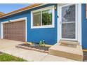 Close up of home's entrance highlighting the blue stucco, brown garage door, and nicely landscaped entry at 18662 E Brown Pl, Aurora, CO 80013