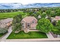 Aerial view of brick house, large front lawn, landscaping, and golf course community at 7758 Edgewater Ct, Lone Tree, CO 80124