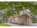 Side exterior view of home with brick facade, three-car garage, and mature trees at 7758 Edgewater Ct, Lone Tree, CO 80124