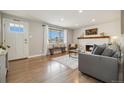 Bright living room with a brick fireplace, hardwood flooring, and large windows at 1667 S Balsam Ct, Lakewood, CO 80232