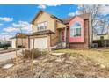 Tan two-story house with a red accented bay window and mature landscaping at 7711 Xavier Ct, Westminster, CO 80030