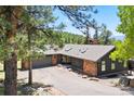 Ranch-style home featuring stone accents, a two-car garage, and a well-maintained asphalt driveway at 1555 Genesee Ridge Rd, Golden, CO 80401
