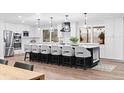 Modern kitchen featuring white cabinets, stainless appliances, and an expansive island with pendant lighting at 9939 E Aberdeen Ave, Englewood, CO 80111