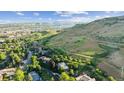 Scenic aerial view of hillside homes nestled among lush greenery and distant mountain range at 14150 Foothill Ln, Golden, CO 80401