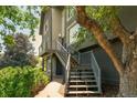 Modern home exterior with stairs leading up to a deck and lush landscaping at 14150 Foothill Ln, Golden, CO 80401