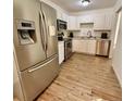 A well-lit kitchen featuring stainless steel appliances, white cabinetry, and hardwood flooring at 6800 E Tennessee Ave # 351, Denver, CO 80224