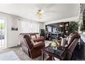 Comfortable living room with ceiling fan and large TV atop a fireplace console at 12167 E Exposition Ave, Aurora, CO 80012