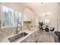 Modern kitchen with white cabinets, stainless steel sink, and stylish backsplash, complemented by a cozy dining area at 10763 Lewis Cir, Broomfield, CO 80021