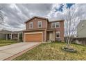 Two-story home with neutral siding and a well-manicured lawn and driveway at 303 Diablo Pl, Brighton, CO 80603