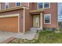 Close up view of the front door and attached two car garage with landscaping at 303 Diablo Pl, Brighton, CO 80603