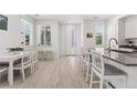 Bright, open kitchen and dining area featuring white cabinets, stainless steel appliances, and wood-look floors at 12314 Hayloft Ln, Thornton, CO 80241